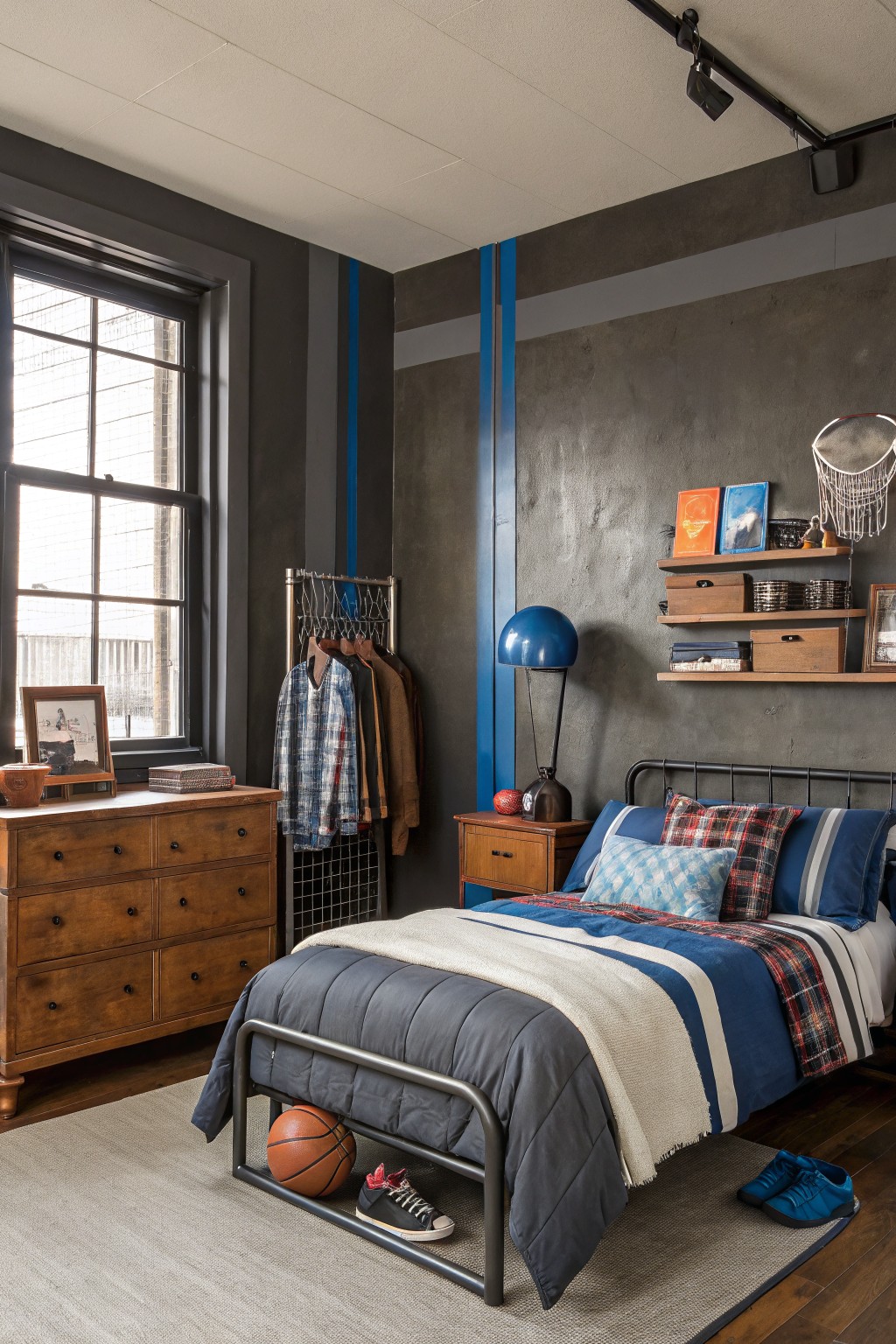 A boy's bedroom with dark gray walls and vertical blue stripes.