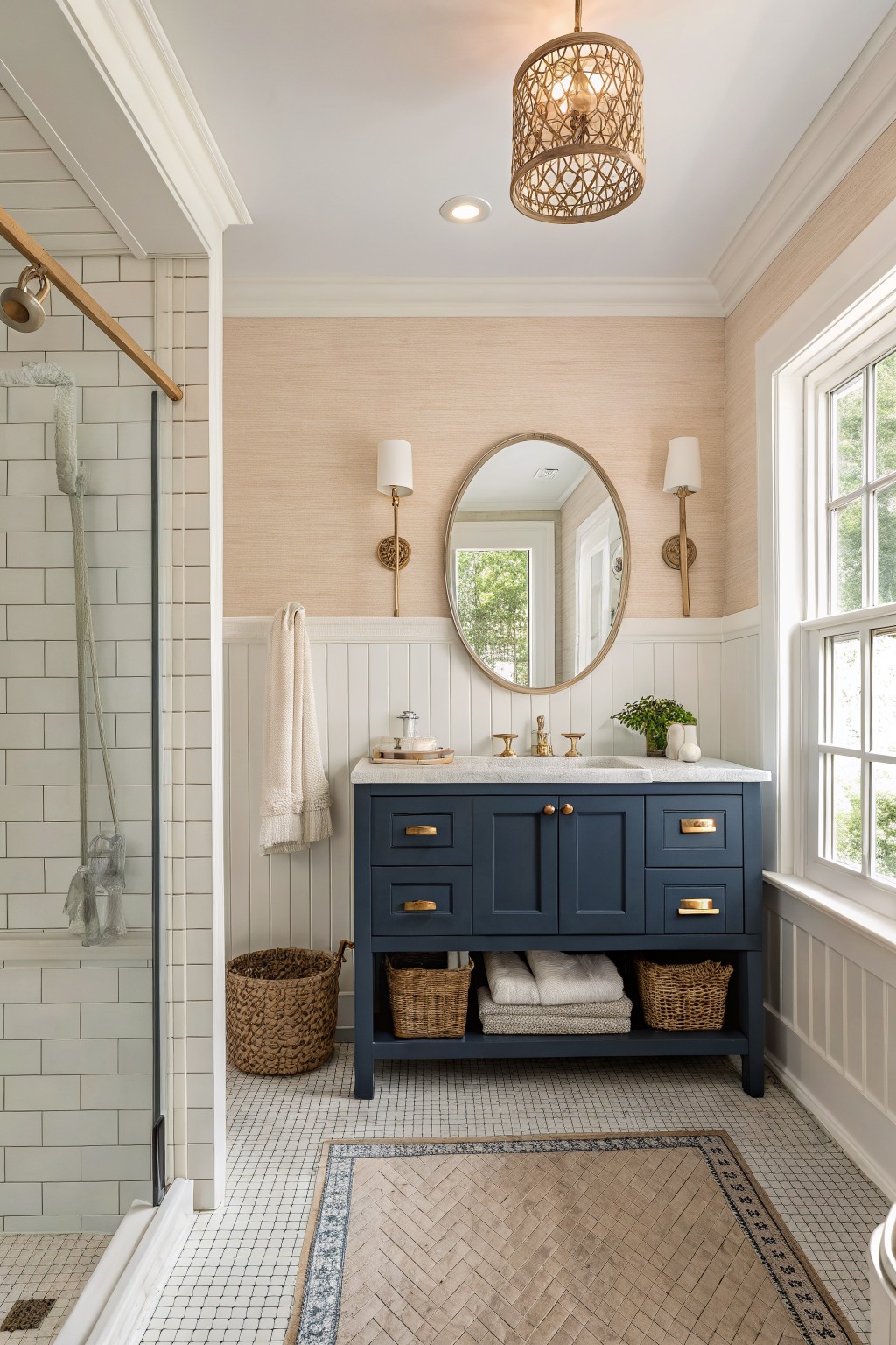 A bathroom with soft beige walls above white wainscoting and a dark blue vanity.