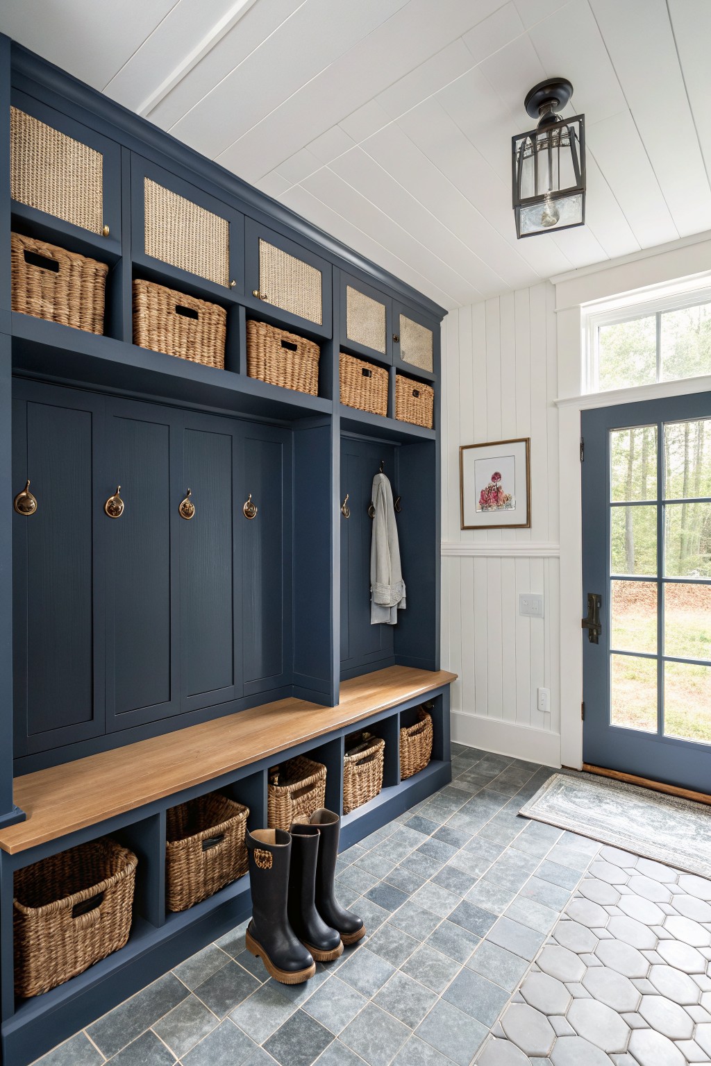 Navy blue mudroom with bench, woven baskets, black boots, and blue door.