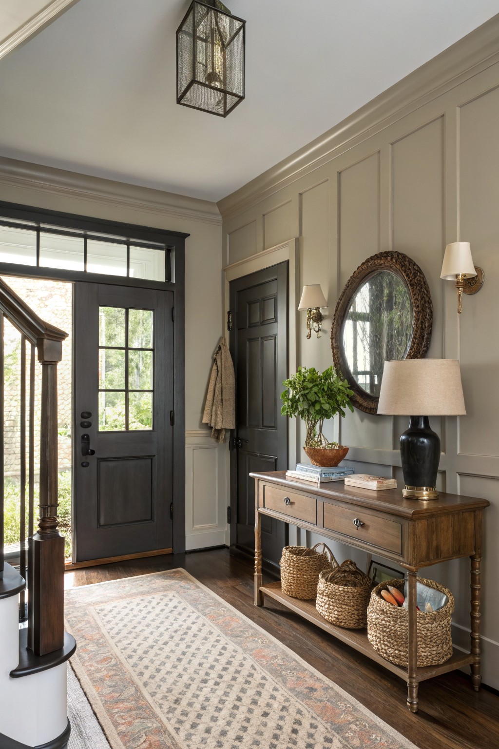 A hallway with soft greige walls, dark doors, and a wooden console table.