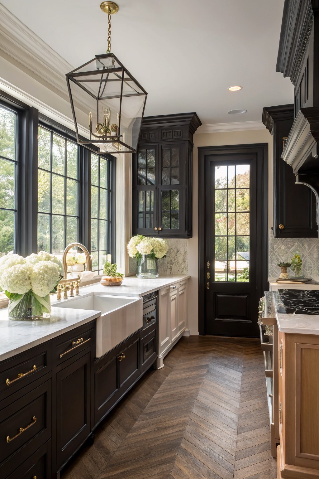 Elegant kitchen with dark cabinets, marble counters, farmhouse sink, and herringbone wood floor.