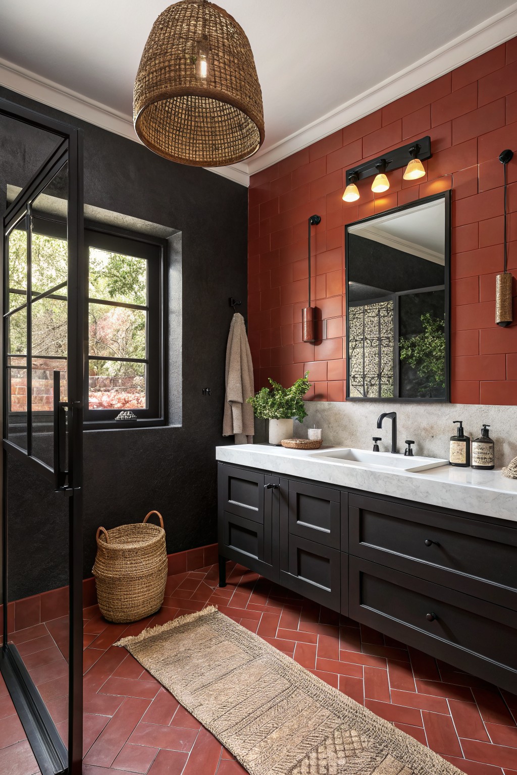A bathroom featuring deep black painted walls beside red tile and a white marble vanity.