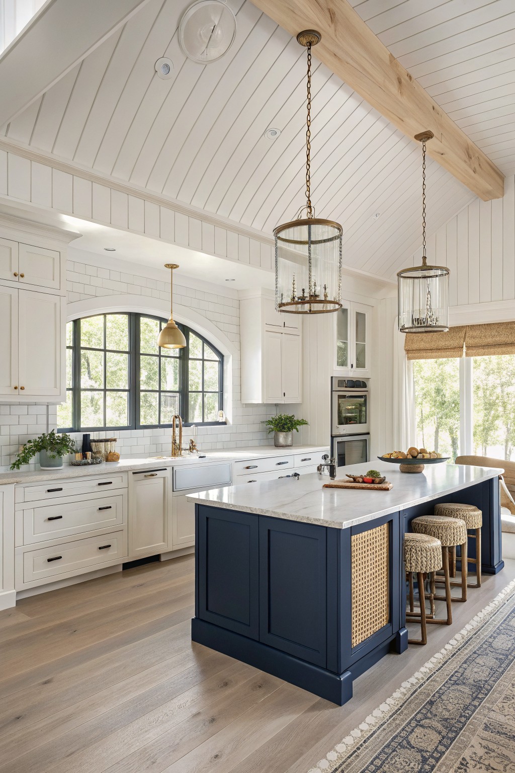 Warm cream cabinets in a kitchen with a navy island and wood floors.