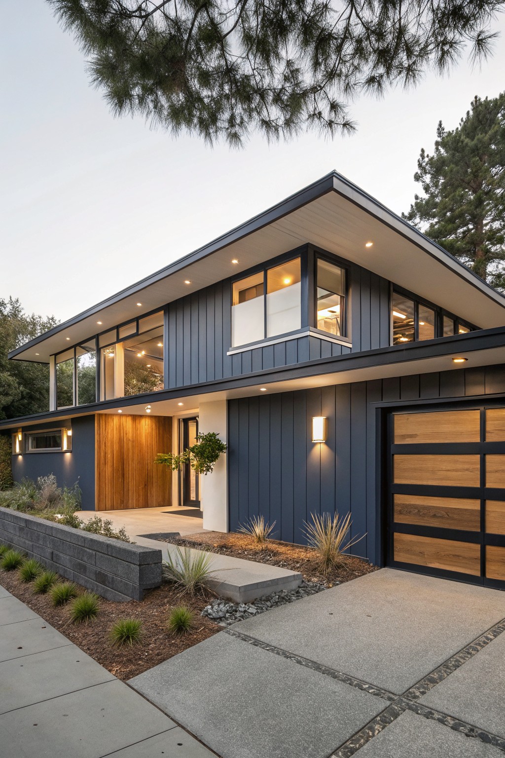 Modern dark blue house with wooden garage, large lit windows, and concrete driveway.