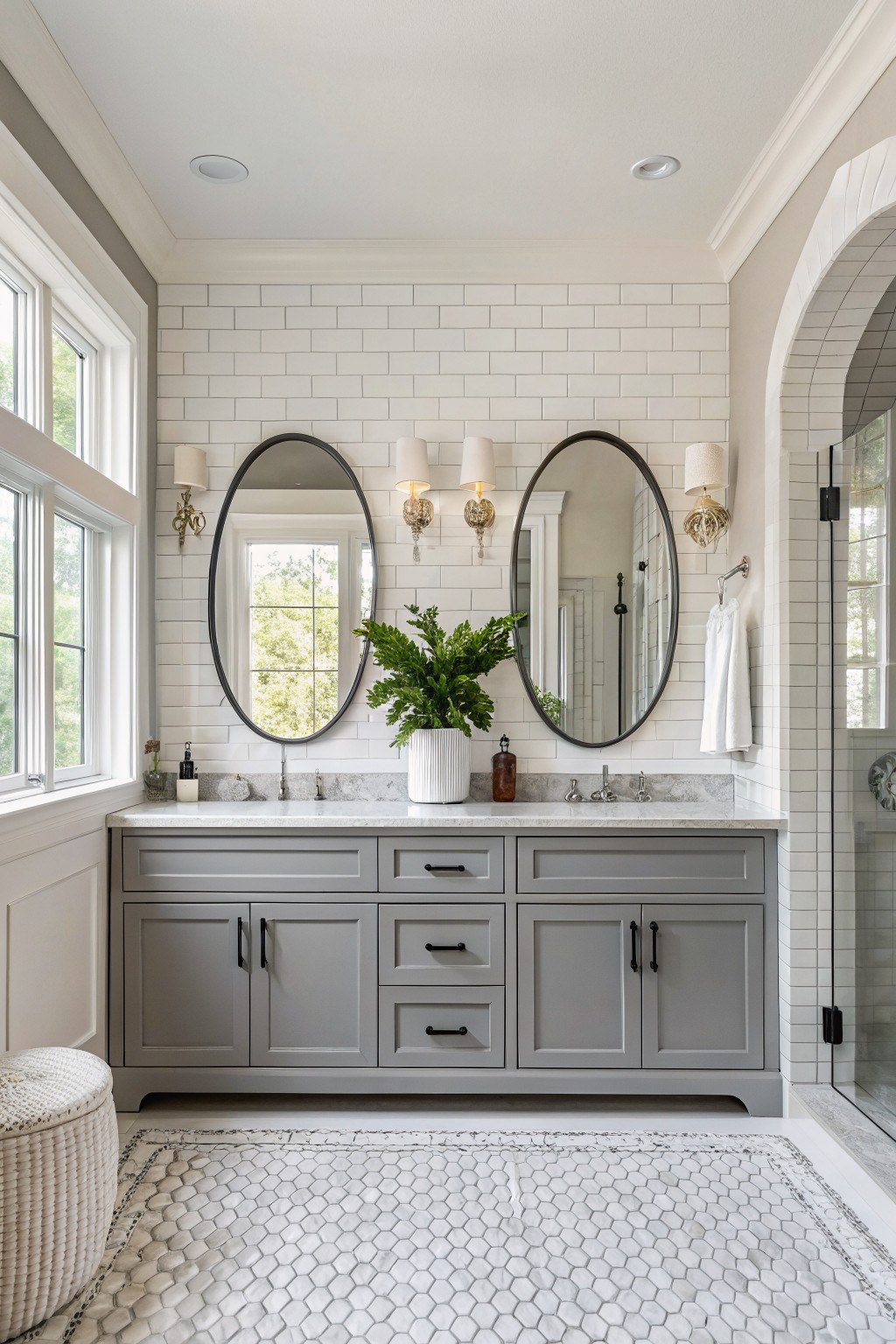 Gray painted vanity with white marble top in a bathroom with subway tile walls.