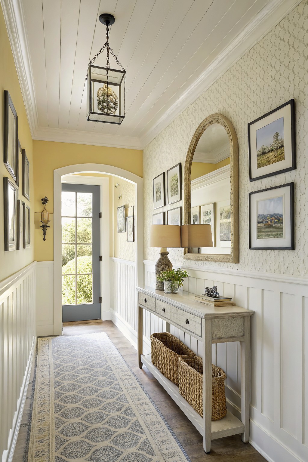 A hallway with soft yellow walls and white wainscoting.
