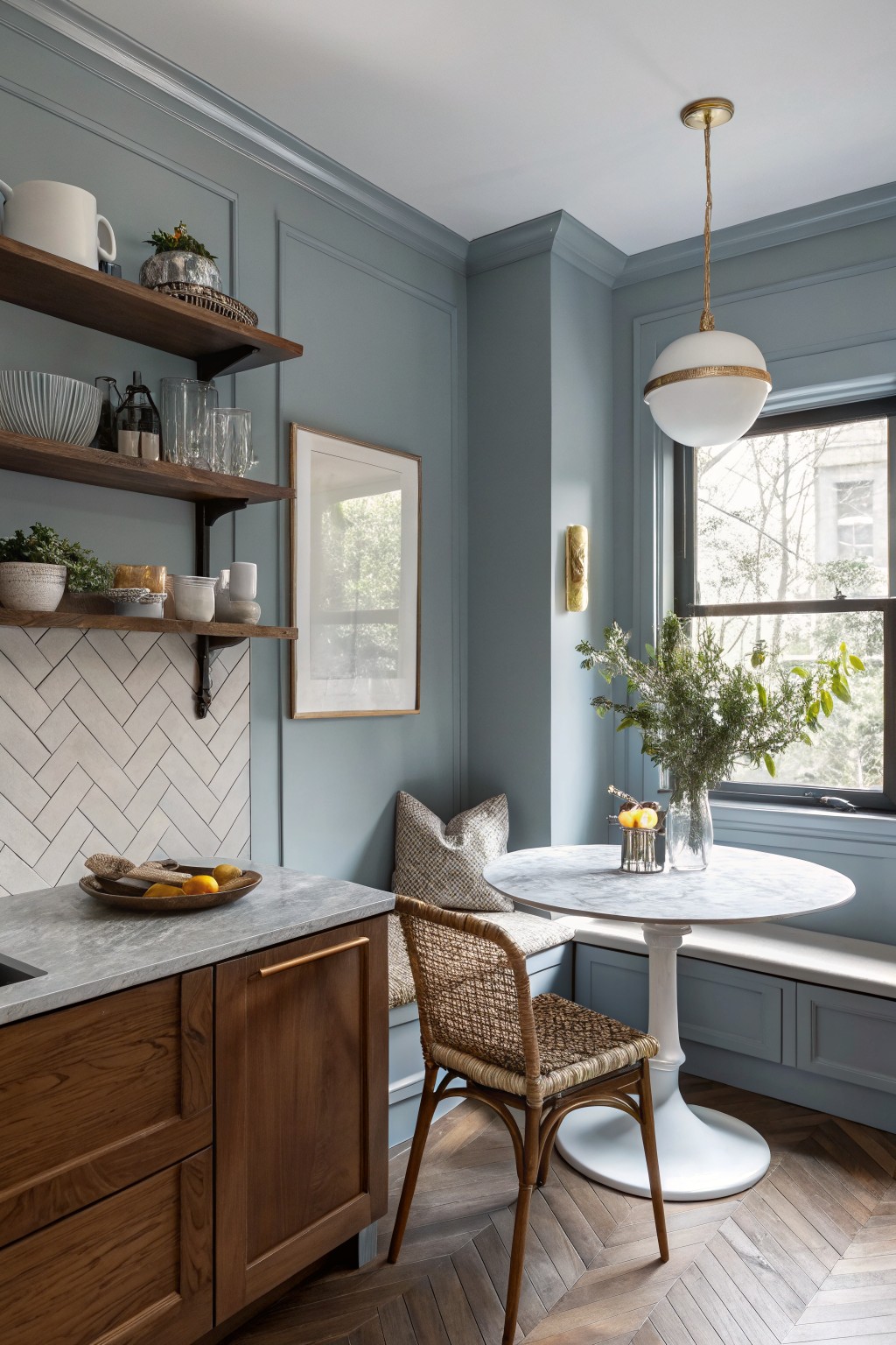 Soft blue gray walls in a kitchen with wood cabinetry and a round table by the window.
