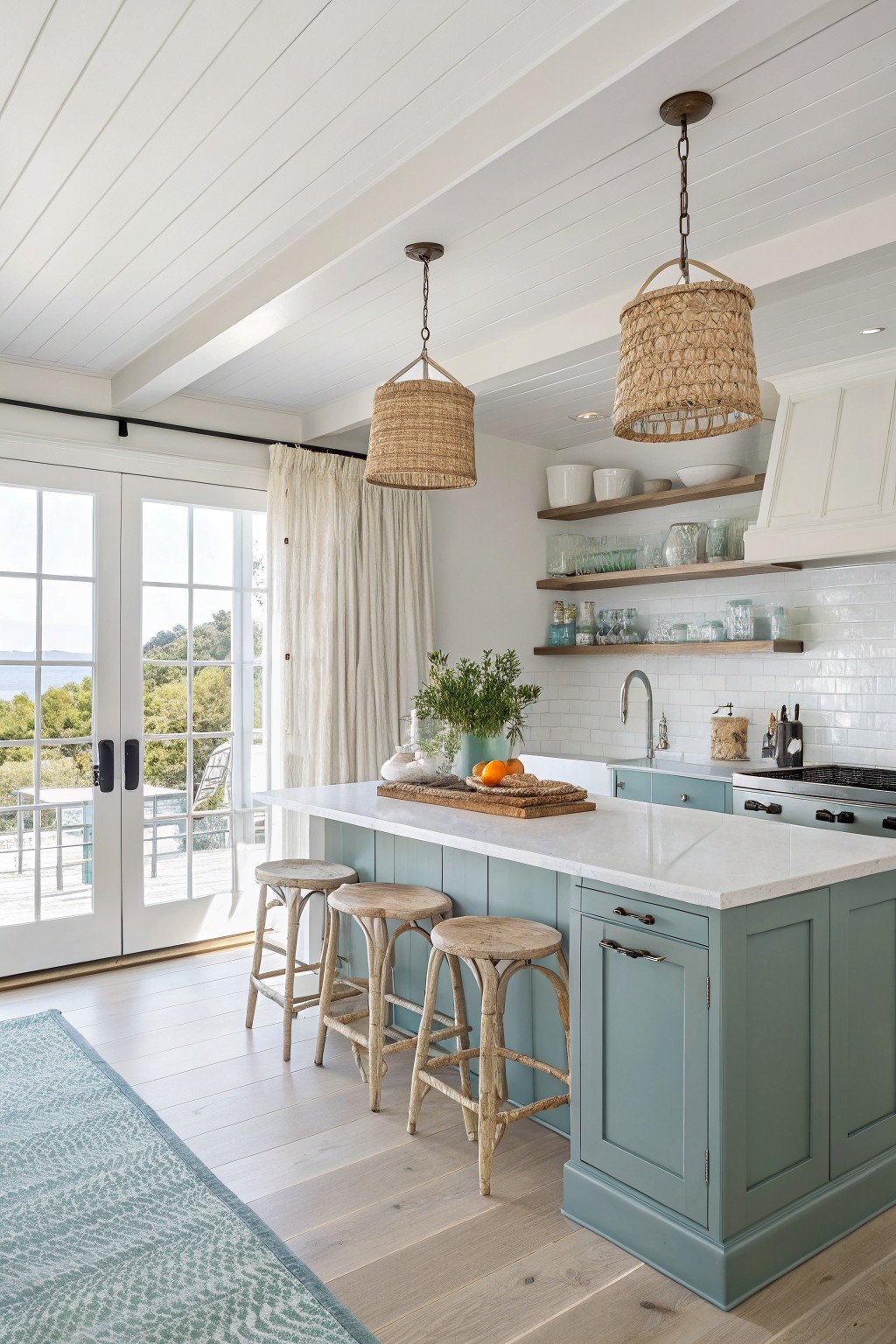 Coastal kitchen with sage green island, marble countertop, woven pendants, and ocean-view doors
