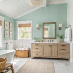 Light blue green walls in a bathroom with white vanity and marble counters.