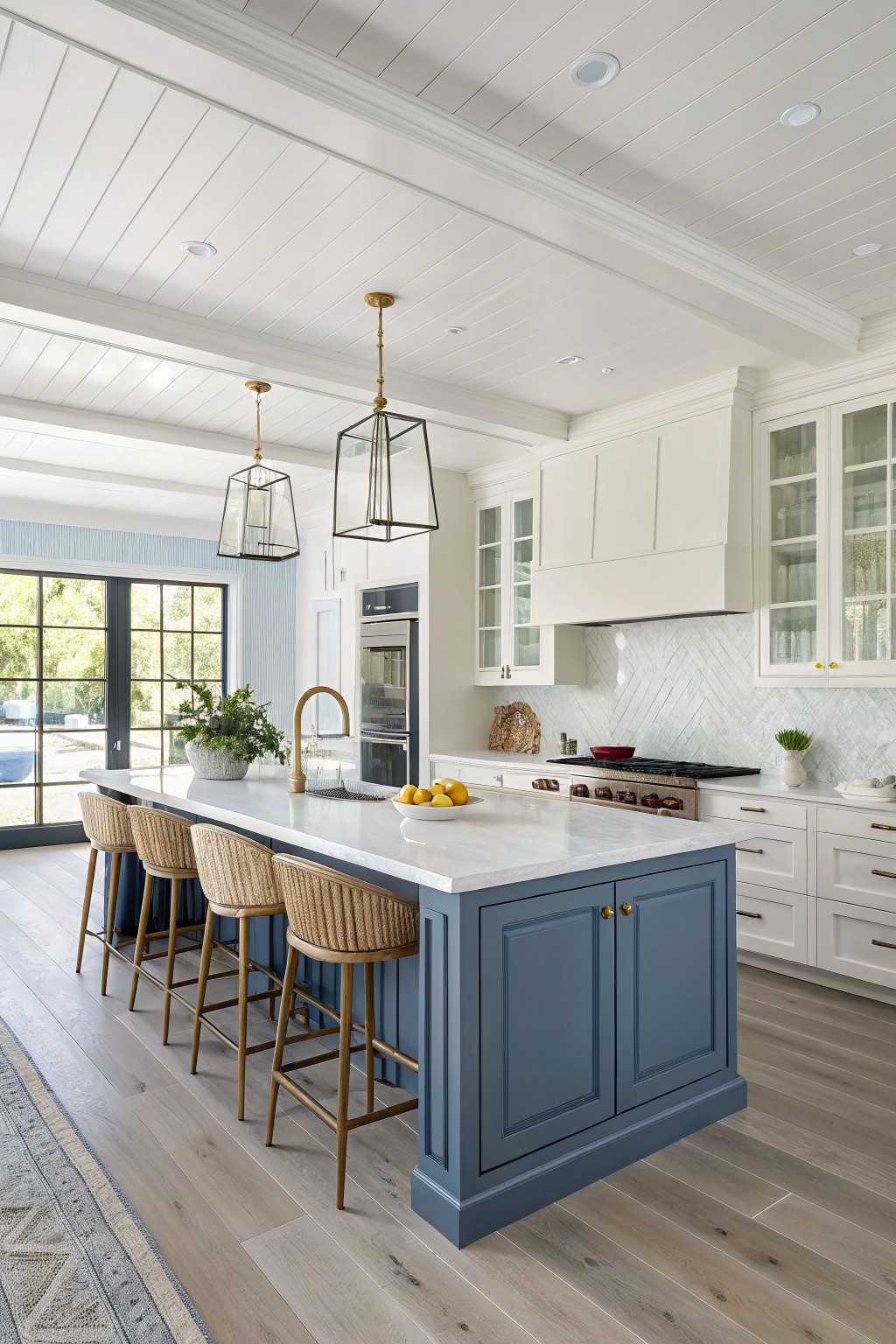 Modern kitchen with blue island, white marble counters, and woven bar stools