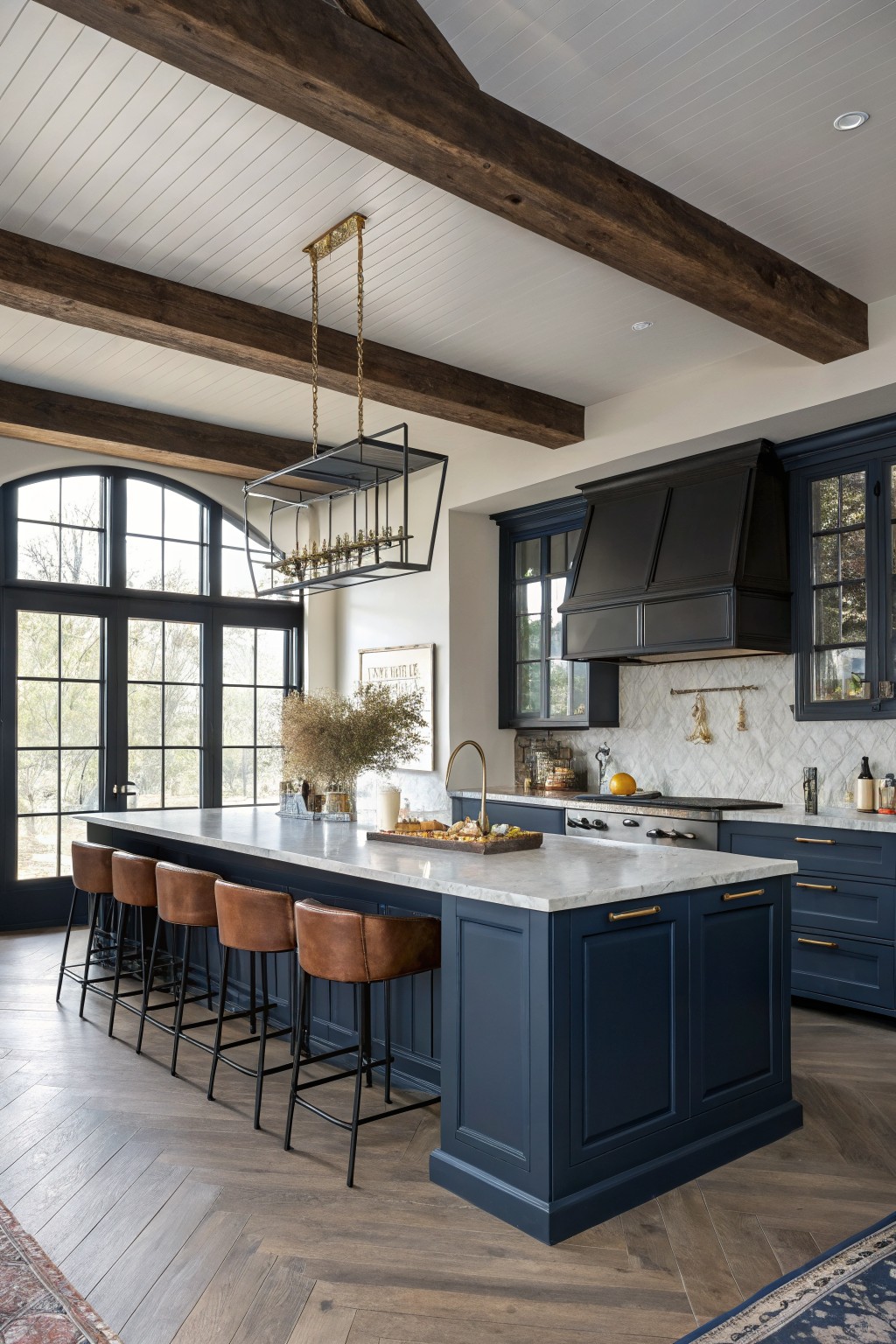 Navy blue kitchen cabinets with a white marble countertop and brass hardware.