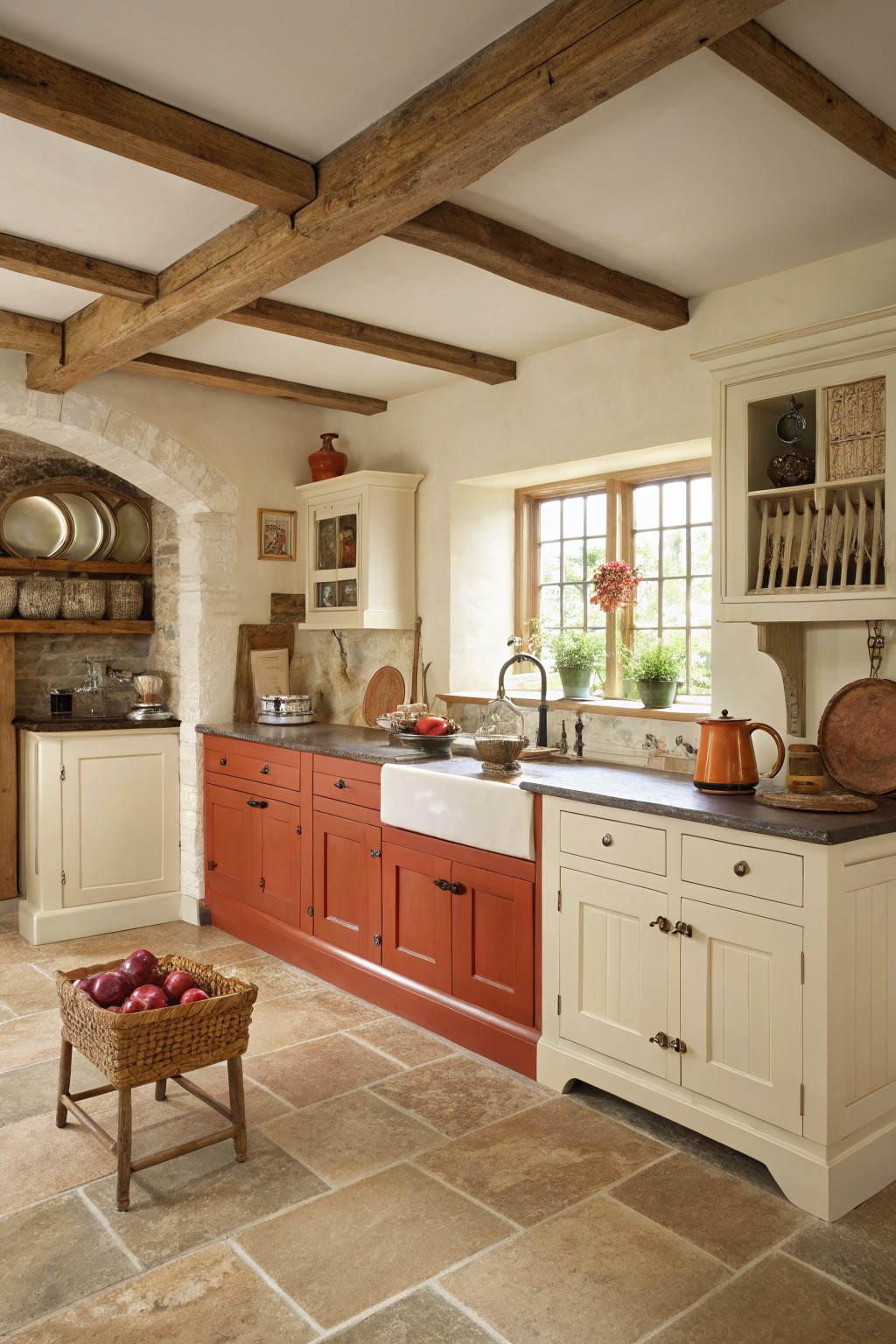 Warm terracotta and cream kitchen cabinets with a farmhouse sink and exposed wood beams.