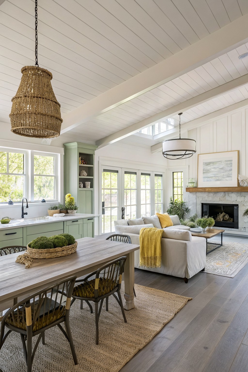 Sage green cabinetry in an open kitchen and living area with white walls and wood floors.