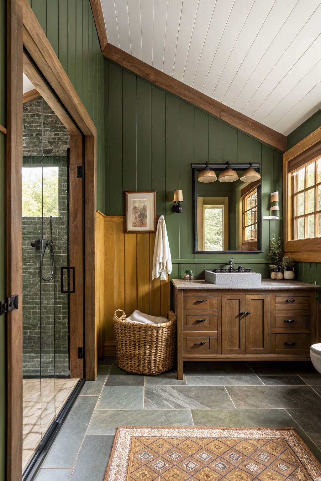A bathroom featuring deep green walls with wood cabinetry and stone flooring.