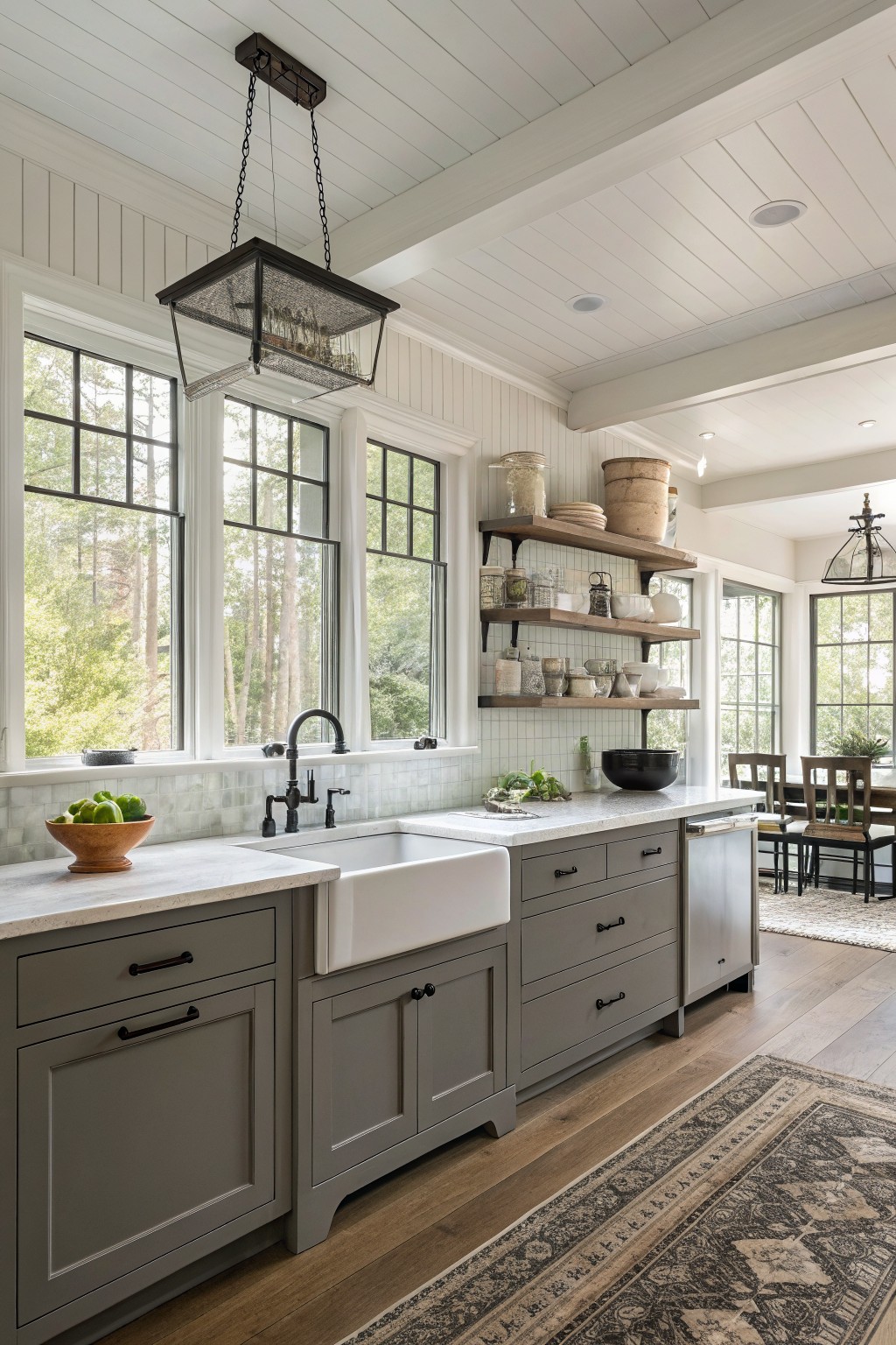 Gray painted cabinets in a bright farmhouse kitchen with white windows and open shelving.