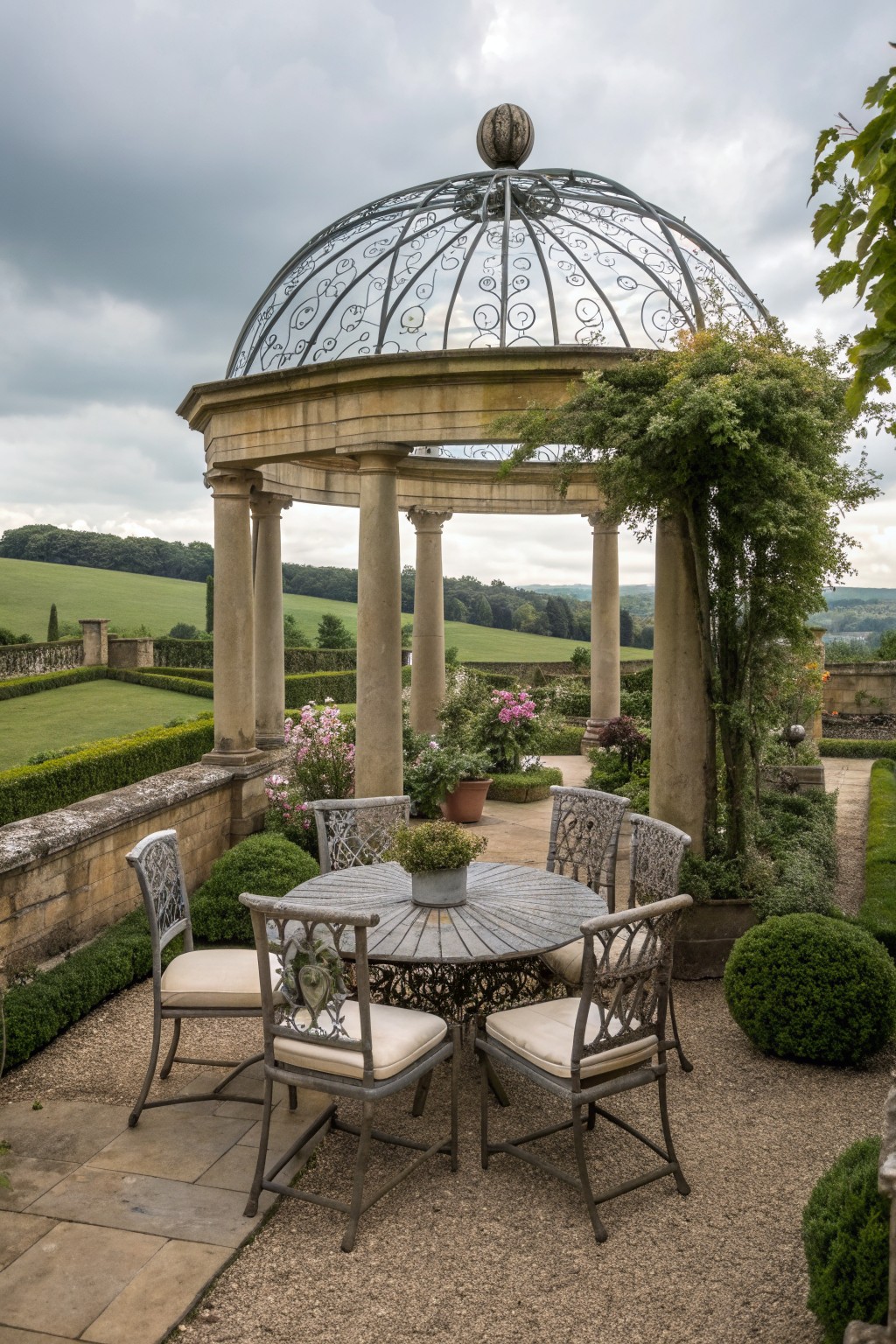 Ornate stone gazebo with iron dome over round table and chairs in formal garden