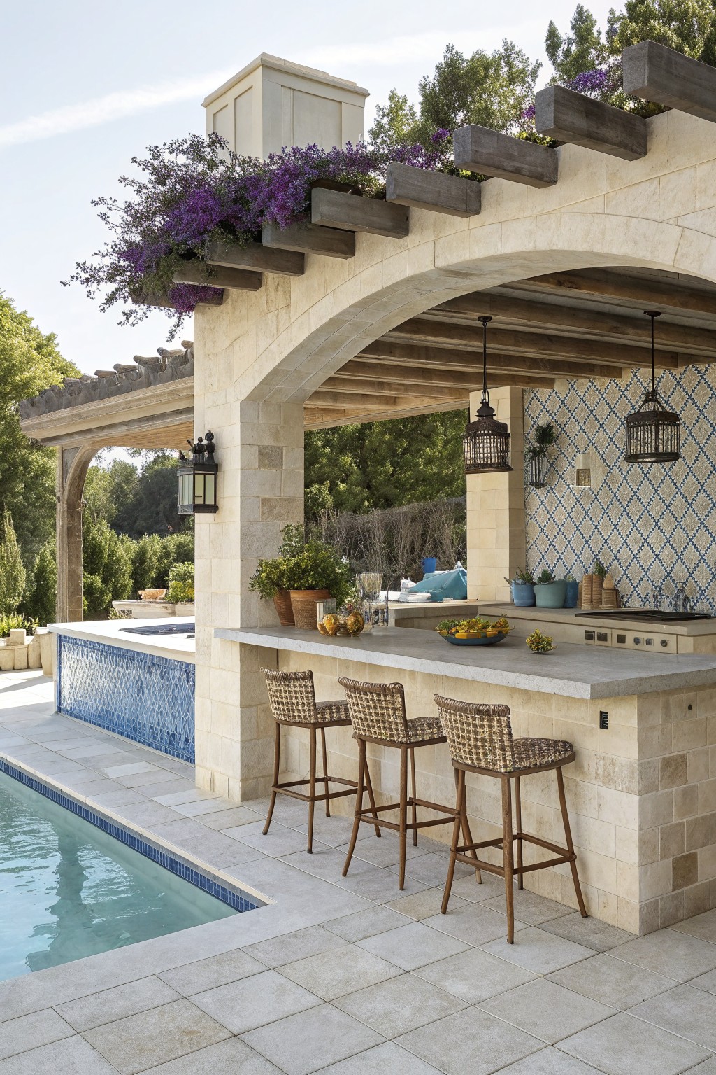 Outdoor stone bar with three counter-height woven stools facing a gray countertop beside a swimming pool under a wooden pergola.