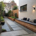 Narrow outdoor side yard with built-in bench seating along a brick wall, gray stone pavers, and potted plants.
