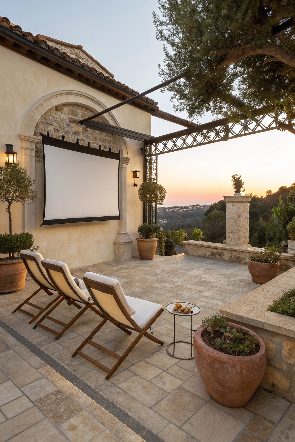 Three lounge chairs on tiled patio facing projection screen at sunset with potted plants